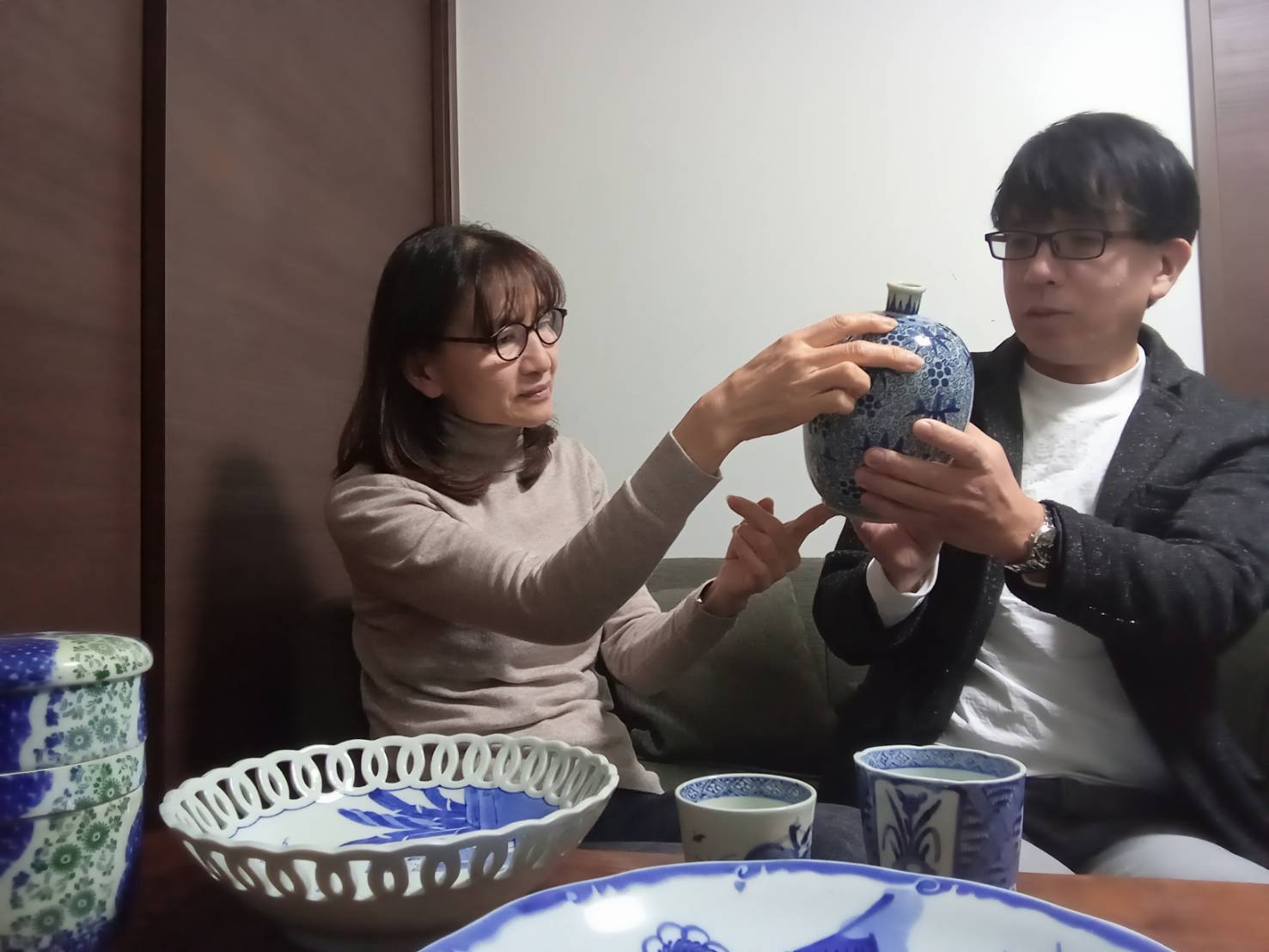 骨董品の査定風景|鑑定士とお客様が青磁の壺を丁寧に確認する様子