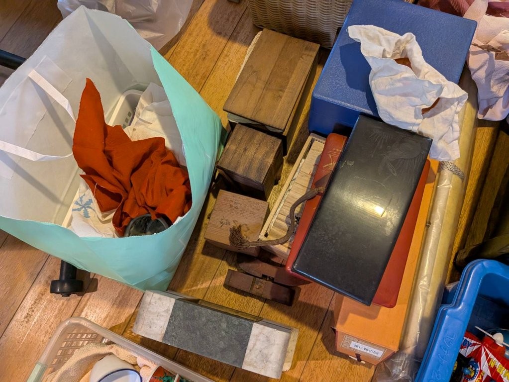 木箱や桐箱、黒塗りの文箱、赤絵の陶磁器などが並ぶ遺品整理中の茶道具類