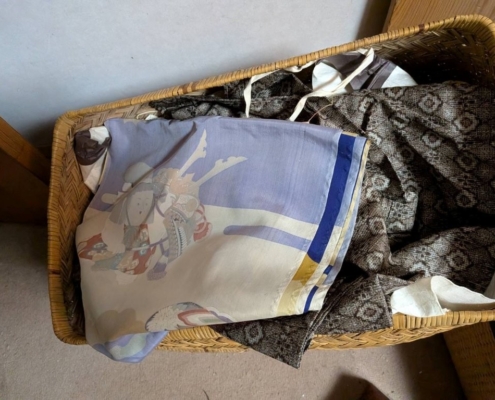 世田谷区上祖師谷のご実家整理中に見つかった泥大島紬を含む着物を籠から取り出し、生地の風合いや織りの状態を確認する鑑定士の手元