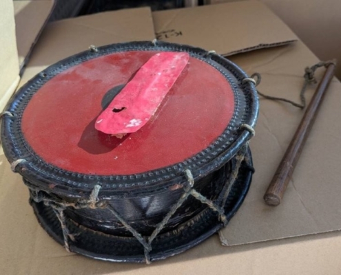 赤い皮面の小型和太鼓（鼓・太鼓類）と撥が並ぶ全体写真（締め紐が見える）